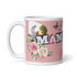 Seitenansicht einer weißen Fototasse für Mamas mit sichtbarem Henkel links, einem Herz-Foto-Ausschnitt, Schmetterlingen und rosafarbenen Blumen-Illustrationen auf rosa Hintergrund.