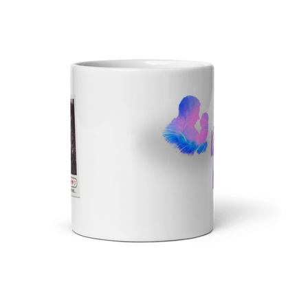Vorderansicht einer weißen Tasse mit dem geschwungenen, blau-violetten Schriftzug „Du wirst Papa!“ und einer farbigen Aquarell-Silhouette, die einen Mann zeigt, der ein Baby hält.