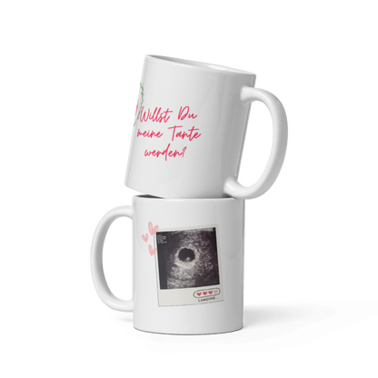 Zwei weiße Kaffeetassen übereinander gestapelt: Die obere zeigt den pinken Schriftzug „Willst Du meine Tante werden?“, die untere ein Ultraschallbild im Polaroid-Stil mit kleinen Herzen.