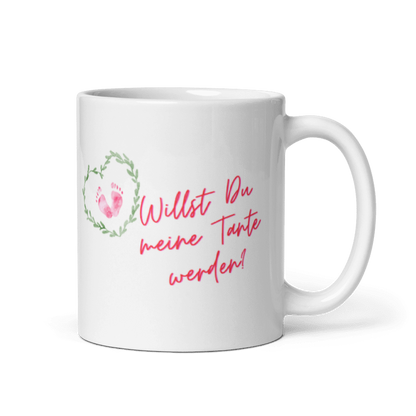 Seitenansicht einer weißen Tasse mit Henkel rechts, bedruckt mit dem pinken Spruch „Willst Du meine Tante werden?“ und einem kleinen Blätterherz mit Babyfüßen.