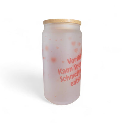 Ein mattiertes Glas mit Bambusdeckel, verziert mit einem zarten Motiv aus Herzen, Rosen und einem Papierflieger im Design „Schmetterlingsmomente“.