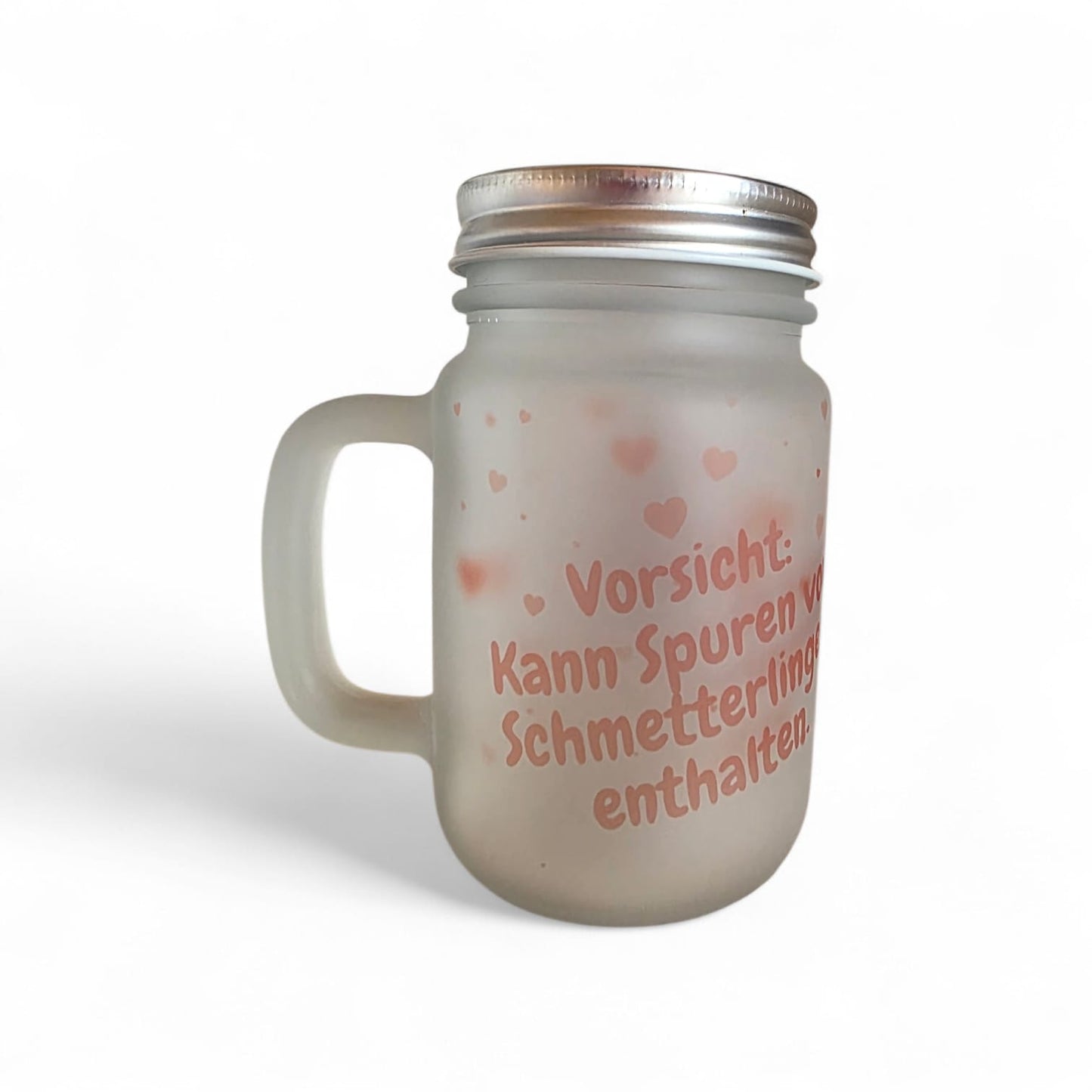 Detailaufnahme des mattierten Henkelglases „Schmetterlingsmomente“ mit dem aufgedruckten Spruch „Vorsicht: kann Spuren von Schmetterlingen enthalten“.