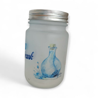 Detailaufnahme eines mattierten Trinkglases mit einer blauen Zaubertrank-Flaschen-Illustration und einem angedeuteten Wasserspritzer-Design an der Seite.
