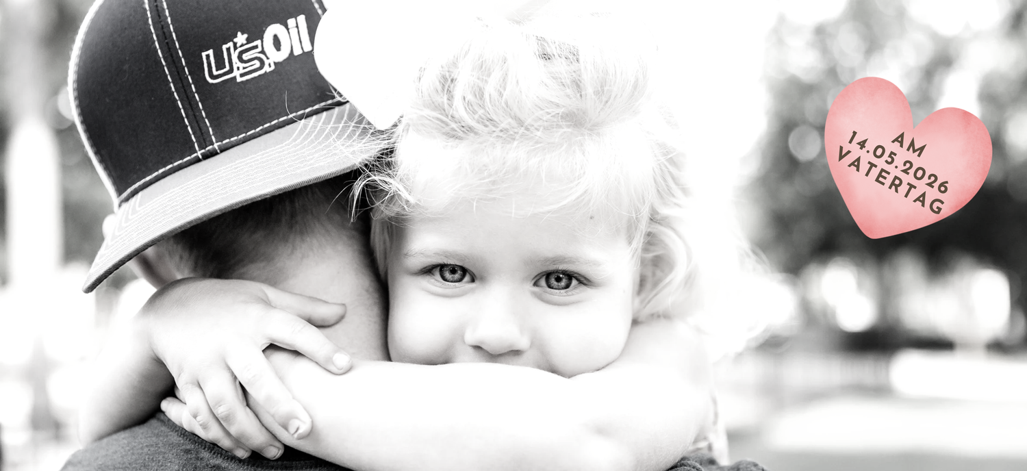 Ein emotionales Schwarz-Weiß-Foto von zwei Kindern, die sich umarmen, passend zum Vatertag am 14.05.2026. Im Hintergrund ist ein Herz mit dem Datum zu sehen. Eine perfekte Geschenkidee von Schlucksachen.