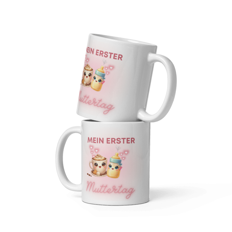Zwei gestapelte weiße Tassen von Schlucksachen mit dem Aufdruck Mein erster Muttertag, illustriert mit einer niedlichen Kaffeetasse, einem Babyfläschchen und rosa Herzen.